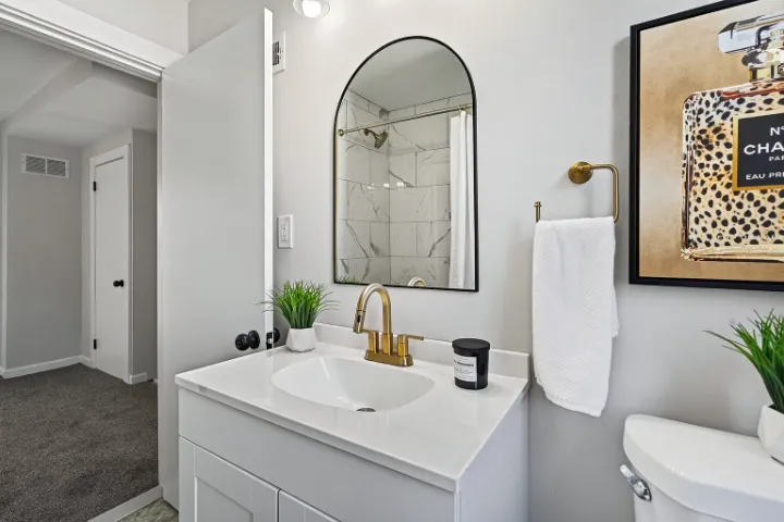 Bathroom vanity with arched mirror and brass faucet