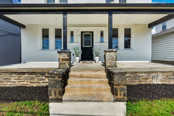 Covered front porch with stone piers and a black front door